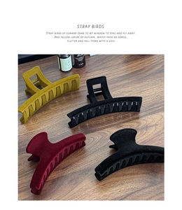 Detailed view of large flocked shark hair clips in mustard, burgundy and black velvet finish