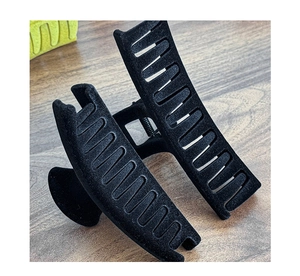 Close-up of large black flocked hair claw clip with a matte finish on a wooden background
