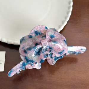 Detail view of pink and blue marbled acetate butterfly hair claw clip on wooden surface