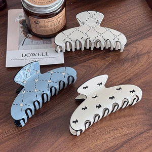 Elegant acetate hair claws with rhinestone and dog pattern on a vintage wooden surface