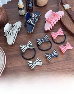 Elegant striped bow hair claw clip set on wooden surface with vintage aesthetic