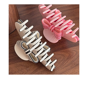 Detail of vintage French ribbon hair claw clips in cream and pink on a wooden desk