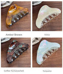 Detail view of four acetate hair claws in amber, beige, dark tortoiseshell and teal colors