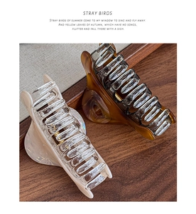 Close-up of premium cream and amber resin hair claws on vintage wooden surface