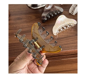 Detail of amber resin hair claw clip showing metallic spring and sturdy grip teeth