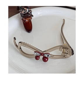Detailed view of a champagne gold banana hair clip with red cherry crystal accents