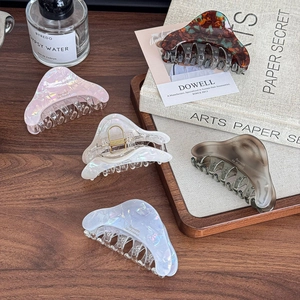 Elegant acetate geometric hair claw clips in assorted patterns on a premium wooden desk