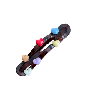 Elegant tortoise shell hair clip with colorful acrylic hearts on a white background