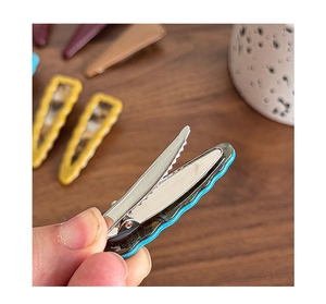 Detailed back view of a wavy resin hair clip showing the metal spring and serrated teeth