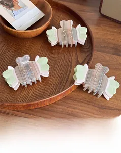 Macro detail of three candy-shaped acetate hair claws with rhinestones on a wooden tray