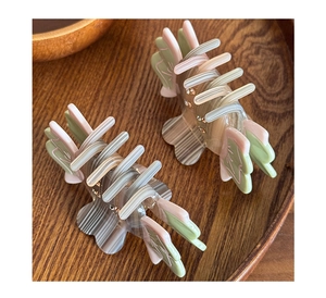 Detailed macro view of acetate hair clips with inlaid rhinestones on a dark wooden tray