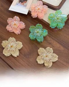 Détail de pinces à cheveux fleur de cerisier en acétate rose et vert élégant