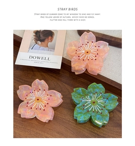 Détail de pinces à cheveux en acétate forme cerisier rose et vert sur fond en bois
