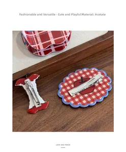 Detail view of retro red gingham apple hair clip with acetate finish and metal duckbill clip