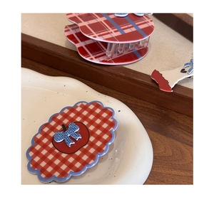 Detail of red and white checkered apple hair clips and bows on a ceramic plate