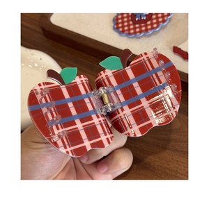 Detail of red and white plaid apple-shaped hair claw clip with green leaf accent