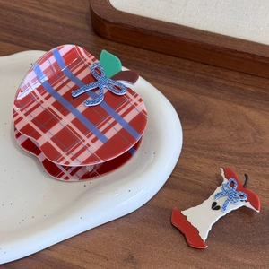 Cute apple-shaped red plaid hair claws and bow hair clips set on a decorative plate