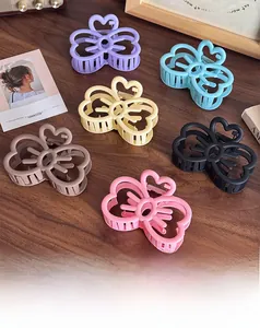 Détail de pinces à cheveux papillon mates en six couleurs sur un bureau en bois vintage