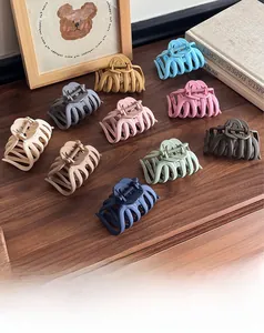 Flat lay of large matte hair clips in eleven varied colors on a wooden background