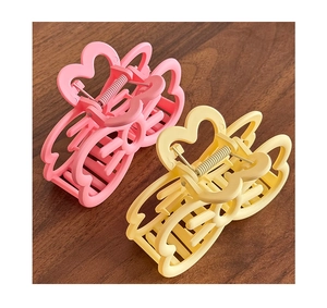 Détail de pinces à cheveux mates en forme de cœur rose et jaune avec ressort en métal