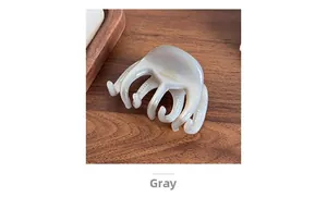 Close-up of grey pearl hair claw clip with golden lettering on elegant dark wood surface