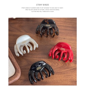 Detailed view of four acetate hair claws in tortoise shell, cream, red, and black finishes
