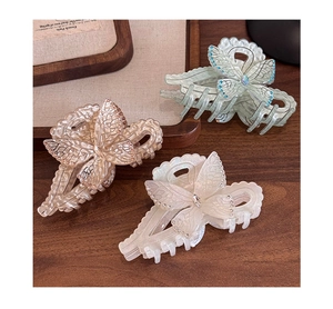 Detailed view of elegant butterfly hair claws in pearl white, champagne, and green colors