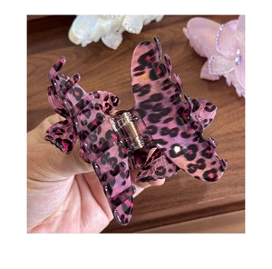 Detailed close-up of a large butterfly hair claw clip with purple leopard pattern and glitter