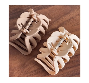 Detailed view of matte beige and nude pink hair claw clips on a dark wood background