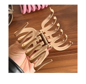 Detail of a large matte khaki hair claw clip held by hand showing its size and grip