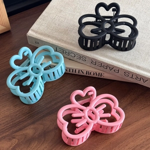 Pinces à cheveux papillon ajourées en noir mat, bleu et rose sur une table en bois