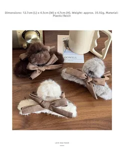 Detailed view of three plush bow hair claws in coffee, grey, and cream on a wooden table