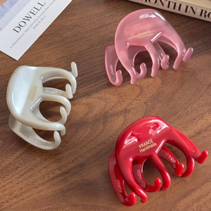 Handmade acetate hair claw clips in pink, white, and red with gold lettering detail