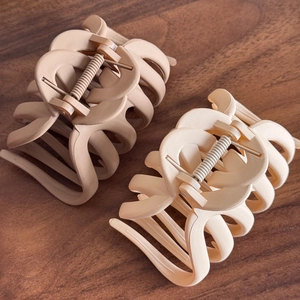Matte finish large claw clips in beige and cream colors on a dark wood background