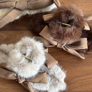 Plush bow hair claw clips in earthy tones displayed on a premium wood texture background