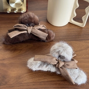 Two plush faux fur bow hair claws in brown and taupe colors on a wooden background