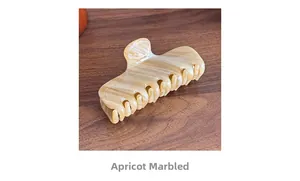 Close-up of elegant apricot striped acetate hair claw clip on dark wood surface