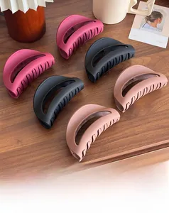 Close-up of large matte silicone hair claws in red, black and beige on wooden table