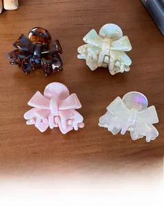 Close-up of small acetate bow hair clips in tortoiseshell, marble green, pink and pearl white
