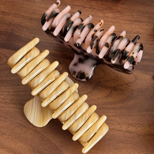 French acetate hair claws in beige and tortoise shell pattern on a dark wood surface
