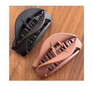 Close-up of black and matte mauve soft silicone shark hair clips on a wood surface