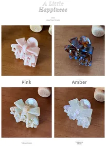 Detail of four acetate bow hair claws in pink, amber, yellow-green and iridescent white