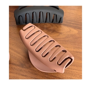 Detailed view of matte pink and black large claw clips on a wooden surface
