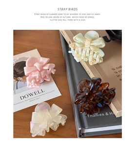 Close-up of four sweet acetate bow hair claws in pink, white, green and tortoiseshell