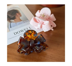 Detail of pink marble and tortoiseshell acetate bow hair clips on a wooden surface