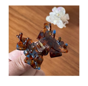Detail view of tortoiseshell acetate bow hair claw clip with blue accents and metal spring