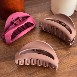 Three-piece set of matte silicone shark hair clips in magenta and mocha on wood desk