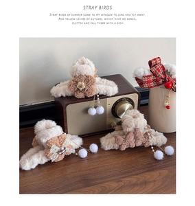 Detail view of plush bow hair claws with lace and pearl pompom tassels in warm tones