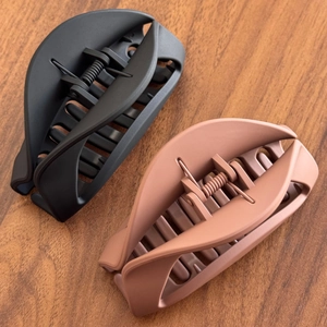 Matte soft silicone shark hair clips in black and brown colors on a wooden surface