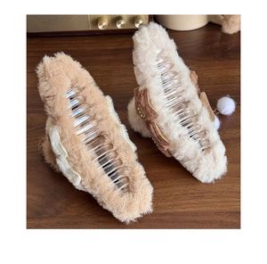 Detail of plush bow claw clips with long fur texture and soft pompom tassels